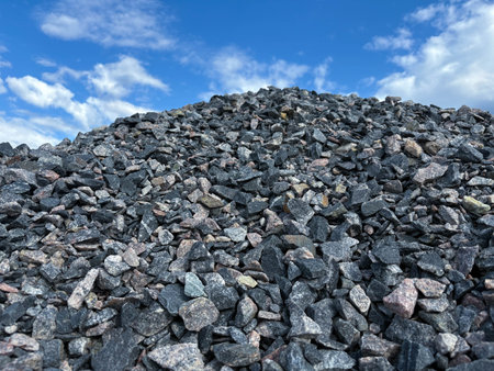 A pile of coarse gravel against a blue sky. Construction material. A large pile of construction rubbleの写真素材