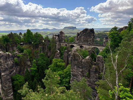 May 2025. The Bastei Bridge in Saxon Switzerland is visible through the greenery of the trees. Editorialの写真素材