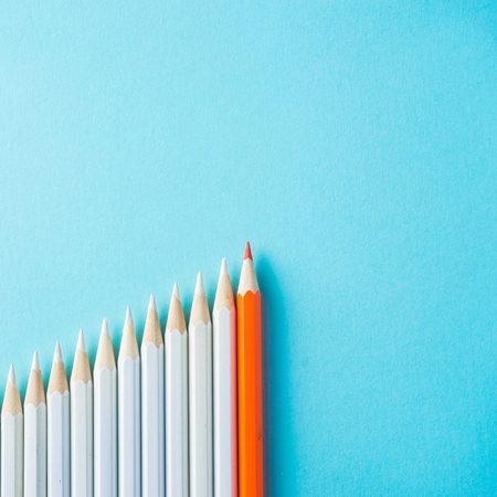 Business concept - lot of white pencils and one color pencil on blue paper background. It's symbol of leadership, teamwork, united and communication.の写真素材