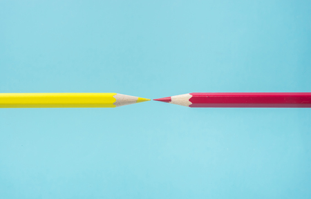 Business concept - yellow and red color pencil floating on blue paper background against each other. It's symbol of fight.の写真素材