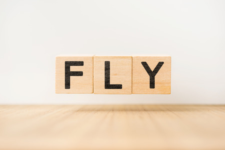Surreal abstract geometric floating wooden cube with vocabulary "FLY" concept on wood floor and white backgroundの写真素材