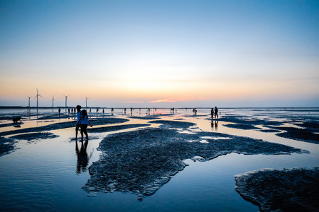 Asia culture - Beautiful landscape of sea level reflect fantasy dramatic sunset sky and people's silhouette in Gaomei wetlands , the famous travel attractions in Taichung, Taiwan.の写真素材
