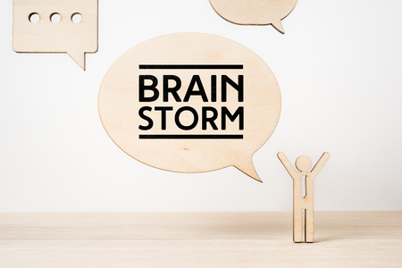 Business and design concept - wooden businessman icon with dialogue frame " brainstorm " on wooden desktop and white backgroundの写真素材