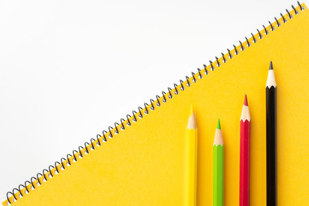Design concept - Top view of yellow spiral notebook and lot of color pencil with leadership concept,...