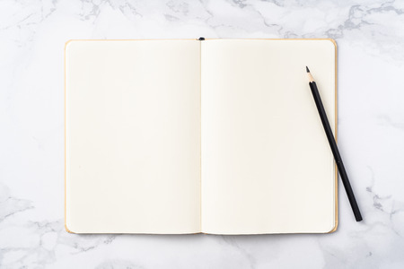 Design concept - Top view of  paper notebook, white page and pencil isolated on marble slabの写真素材