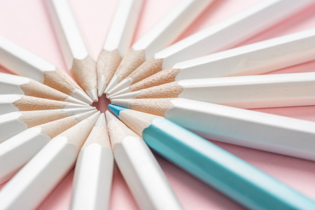 Business and design concept - lot of white pencils and one color pencil on pink paper background. It's symbol of leadership, teamwork, success and unique.の写真素材