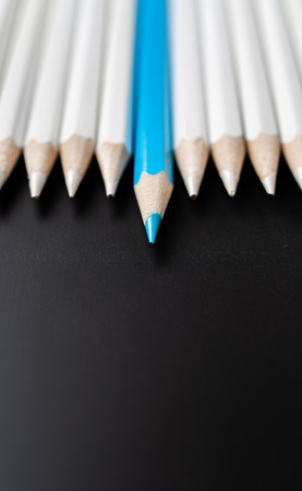 Business and design concept - lot of white pencils and one color pencil on black background. It's symbol of leadership, teamwork, success and unique.の写真素材