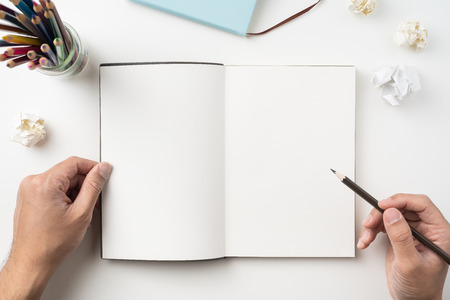 Design concept - Top view of man's two hand hold high grade brown notebook and pen isolated with crumpled paper on white background for mockupの写真素材