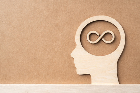 Business and design concept - wooden man head silhouette with infinity icon on kraft paperの写真素材