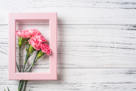 Design concept - top view of bunch of beautiful carnation with photo frame on white vintage wooden...