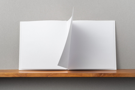 Design concept - front view of opened square white notebook on bookshelf and grey wall for mockupの写真素材