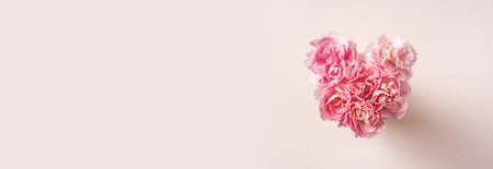 Design concept - top view of bunch of beautiful carnation with heart shape on pink background with copy space for mother day banner mockupの写真素材