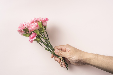 Design concept - top view man hand hold a bunch of carnation with hemp rope on pink background for mother day mockupの写真素材