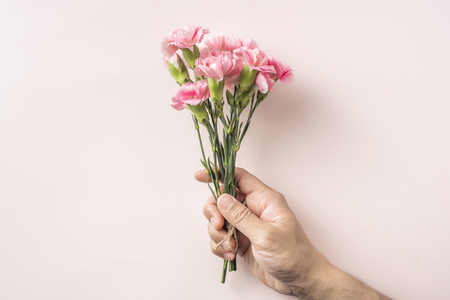 Design concept - top view man hand hold a bunch of carnation with hemp rope on pink background for mother day mockupの写真素材