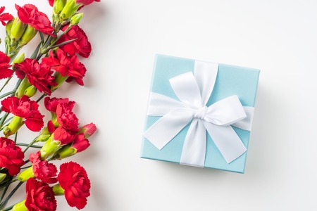 event design concept - top view of a bunch of red carnation and gift box isolated on white background for mothers day and valentines day, wedding event with copy space for mock upの写真素材