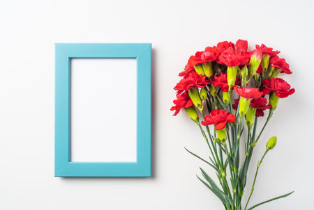 event design concept - top view of a bunch of red carnation and photo frame isolated on white...