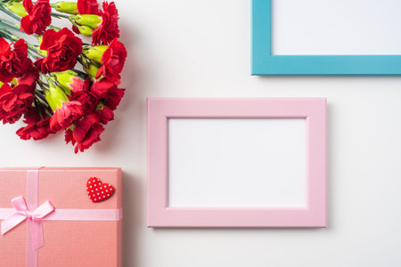 event design concept - top view of a bunch of red carnation and photo frame isolated on white...