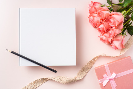 event design concept - top view of a bunch of pink rose , gift box white notebook and vintage ribbon on pink background for mothers day and valentines day, wedding event with copy space for mock upの写真素材