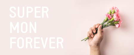 event design concept - top view of a bunch of pink carnation with greeting word hold by mans hand on pink background for mothers day event with copy space for mock upの写真素材