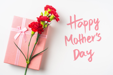 event design concept - top view of a bunch of red carnation and gift box isolated on white background for mothers day and valentines day, wedding event with copy space for mock upの写真素材