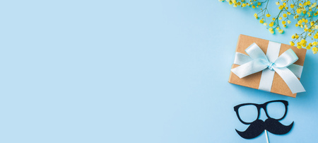 event design concept - top view of fathers day layout with ribbon kraft gift box, yellow flower and gentleman silhouette on blue background, copy space for mock upの写真素材