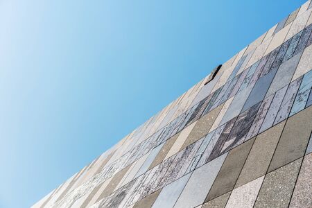 looking up view of stone tile ceramic brick wall background against blue skyの写真素材