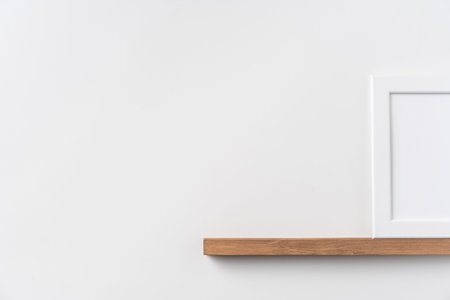 Design concept - front view of vertical white wood photo frame on bookshelf and white wall for...