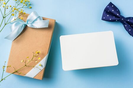 event design concept - top view of fathers day layout with ribbon kraft gift box, yellow flower and necktie on blue background, copy space for mock upの写真素材