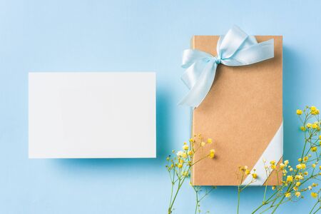 event design concept - top view of fathers day layout with white greeting card, ribbon kraft gift box, yellow flower and white label on blue background, copy space for mock upの写真素材