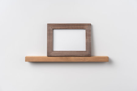 Design concept - front view of horizontal wood photo frame on bookshelf and white wall for mockup