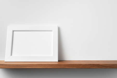 Design concept - front view of horizontal white wood photo frame on bookshelf and white wall for mockupの写真素材