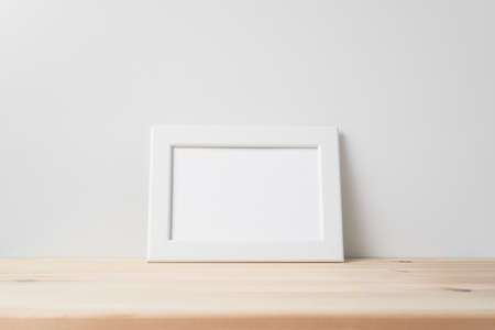 Design concept - front view of horizontal white wood photo frame on wood floor whit white wall for mockupの写真素材