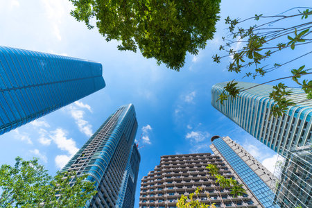 Asia Business concept for real estate, corporate construction and ecology - looking up view of panoramic modern city skyline with blue sky and green tree in Azabudai Hills, tokyo, japanの写真素材
