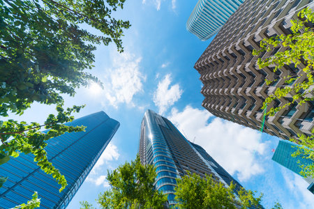 Asia Business concept for real estate, corporate construction and ecology - looking up view of panoramic modern city skyline with blue sky and green tree in Azabudai Hills, tokyo, japanの写真素材