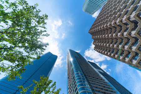 Asia Business concept for real estate, corporate construction and ecology - looking up view of panoramic modern city skyline with blue sky and green tree in Azabudai Hills, tokyo, japanの写真素材