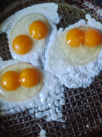 Four fried eggs in a frying pan on a grill.の写真素材