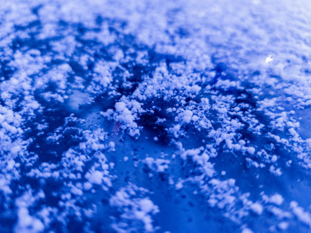 A close up of snow on a blue surface.