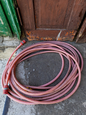 A pink hose laying on the ground next to a wooden door.の写真素材