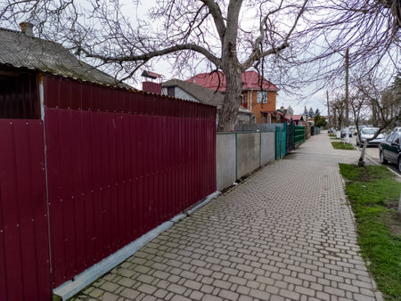 A sidewalk with a red fence and a tree in the middle of it.の写真素材