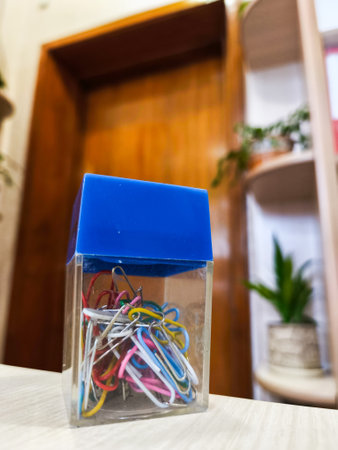A clear box filled with paper clips sitting on top of a table.の写真素材