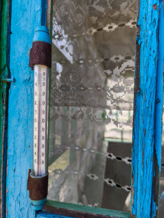 A thermometer hanging from the side of a blue door.の写真素材