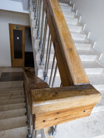 A set of stairs with a wooden handrail in a building.の写真素材