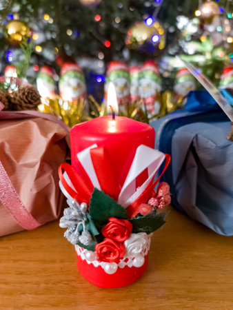 A red candle sitting on top of a wooden table next to a christmas treeの写真素材