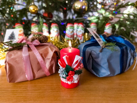 A red candle sitting on top of a wooden table next to a christmas tree.の写真素材