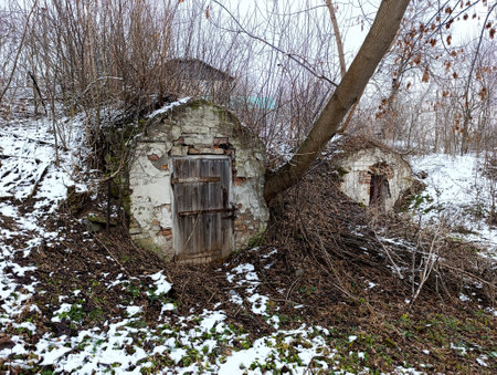 A small stone building with a door in the middle of a snowy forest.の写真素材