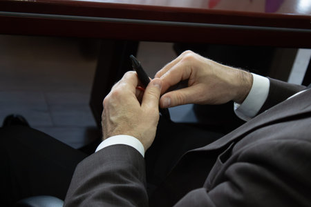 A man in a suit writing on a piece of paper with a pen.