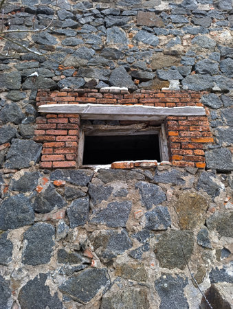 A brick wall with a small window in it.の写真素材