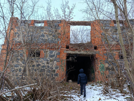 A person walking in front of an abandoned building in the woods.の写真素材