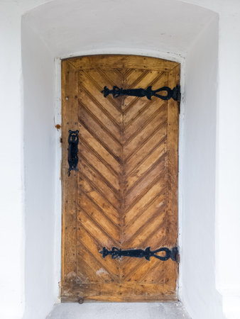 A wooden door in a white wall with a chevron pattern.の写真素材