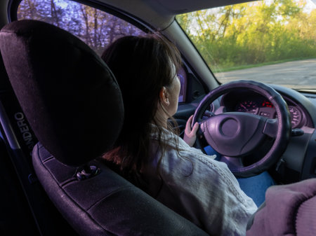 A woman sitting in the driver's seat of a car at night.の写真素材
